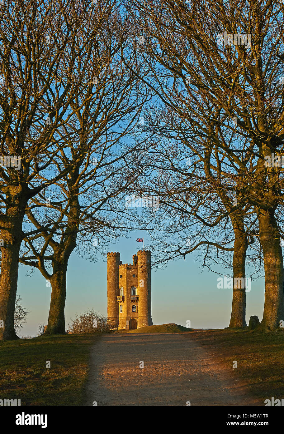 Broadway Tower sur le dessus de la colline de poisson, le deuxième point le plus élevé dans la région des Cotswolds est encadré par quatre arbres feuillus d'un après-midi d'hiver Banque D'Images