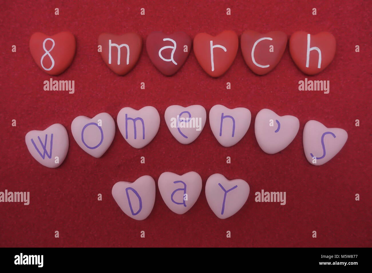 8 mars, Journée de la femme en rouge et rose coeur pierres sur du sable rouge Banque D'Images