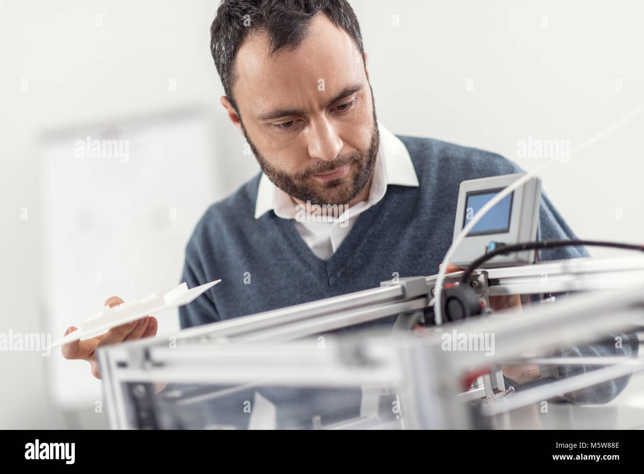 Jeune homme agréable à l'intérieur de l'imprimante 3D Banque D'Images