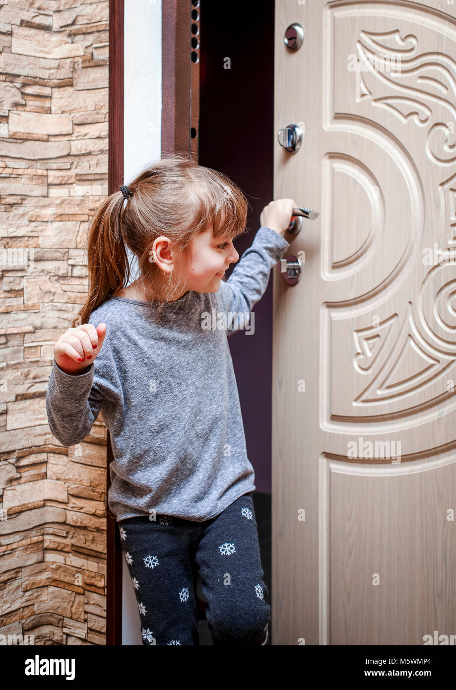 Une petite fille est entrée dans l'appartement et ferme la porte Photo  Stock - Alamy