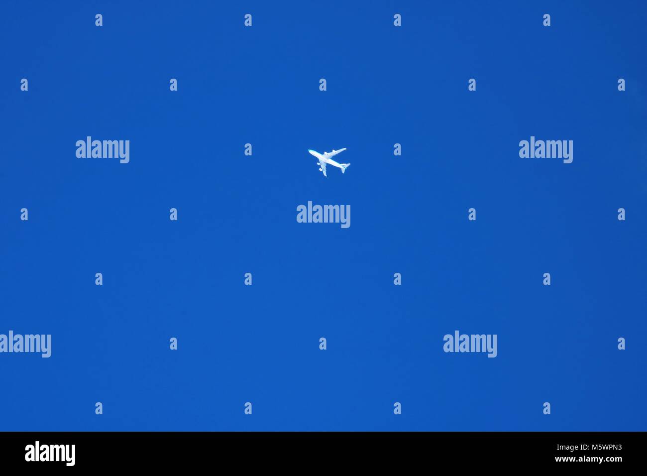 Avion blanc très haut dans un ciel d'hiver bleu Banque D'Images