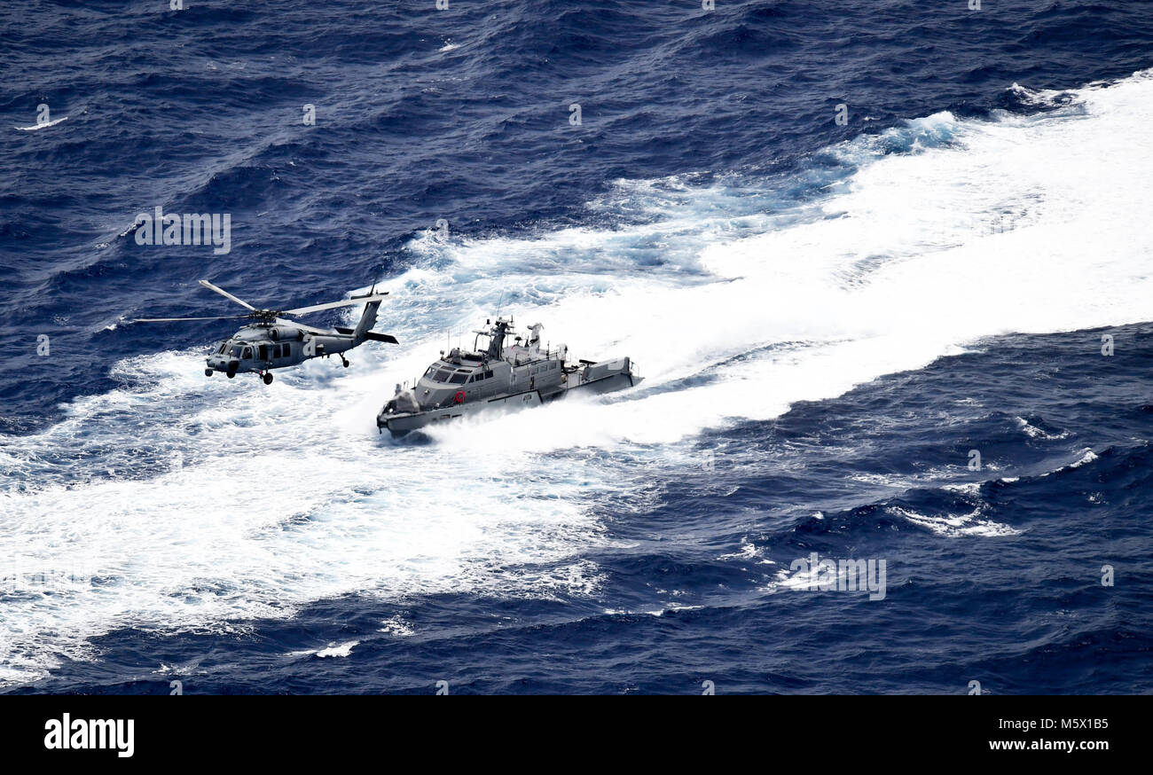 Un MH-60S Sea Hawk, attribué à l'île "Chevaliers" de la mer de l'Escadron d'hélicoptères de combat (HSC) 25, procède à un exercice de recherche et sauvetage d'un bateau de patrouille Mark VI affectés aux zones côtières, Groupe 1 riverains Det. Guam au large de Guam, le 23 février 2018. HSC-25 dispose d'une réception ouverte 24h Recherche et sauvetage et d'évacuation médicale, la posture d'alerte directement en charge de la Garde côtière des États-Unis, secteur Guam et Îles Mariannes région commune. Fluviales côtières Groupe 1, Det. Guam est capable de conduire des opérations de sécurité maritime dans la gamme complète de naval, les opérations interarmées et interalliées. De plus, il fournit des Banque D'Images