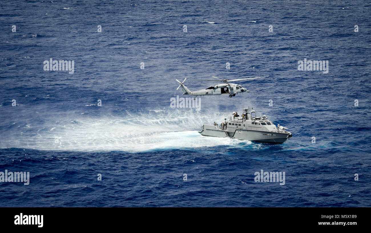 Un MH-60S Sea Hawk, attribué à l'île "Chevaliers" de la mer de l'Escadron d'hélicoptères de combat (HSC) 25, procède à un exercice de recherche et sauvetage d'un bateau de patrouille Mark VI affectés aux zones côtières, Groupe 1 riverains Det. Guam au large de Guam, le 23 février 2018. HSC-25 dispose d'une réception ouverte 24h Recherche et sauvetage et d'évacuation médicale, la posture d'alerte directement en charge de la Garde côtière des États-Unis, secteur Guam et Îles Mariannes région commune. Fluviales côtières Groupe 1, Det. Guam est capable de conduire des opérations de sécurité maritime dans la gamme complète de naval, les opérations interarmées et interalliées. De plus, il fournit des Banque D'Images