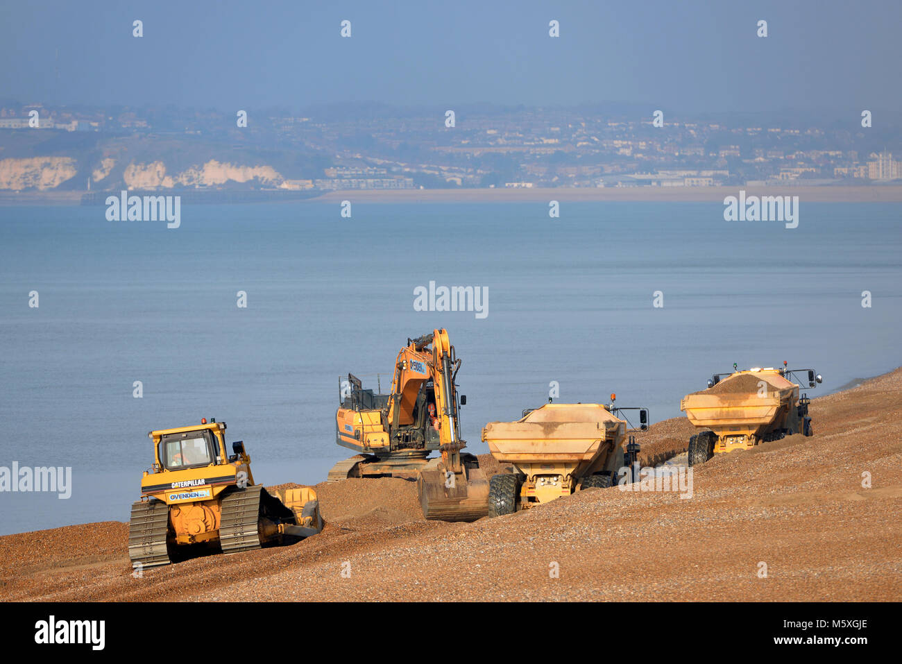 Déménagement de la machinerie lourde sur la plage de galets de Seaford, East Sussex, après les tempêtes d'hiver annuel éroder la plage. Banque D'Images