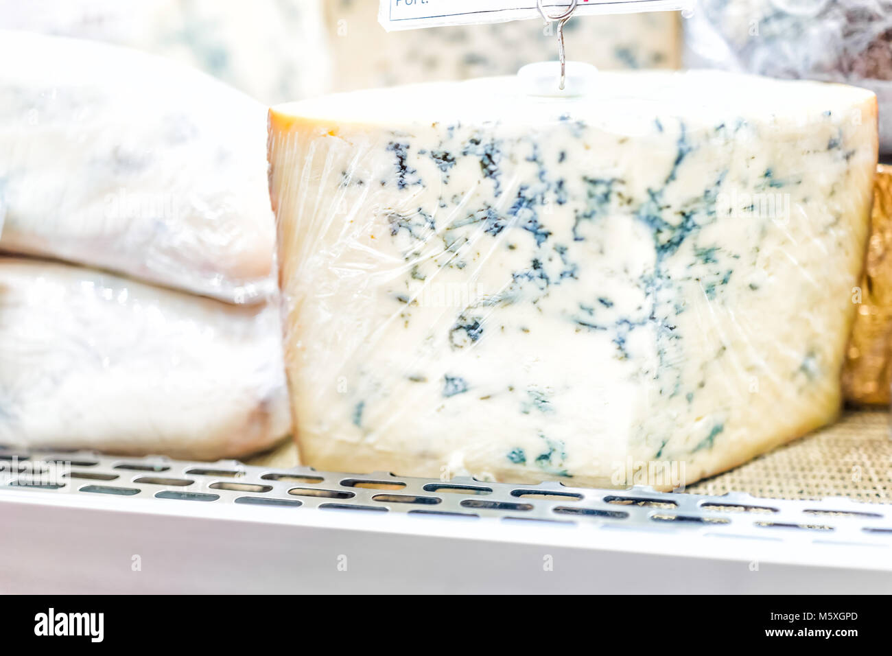 Gros plan macro de fromage bleu partie hunk grand morceau enveloppé dans une pellicule de plastique sur l'affichage vente en magasin supermarché épicerie gourmet boutique moule montrant Banque D'Images