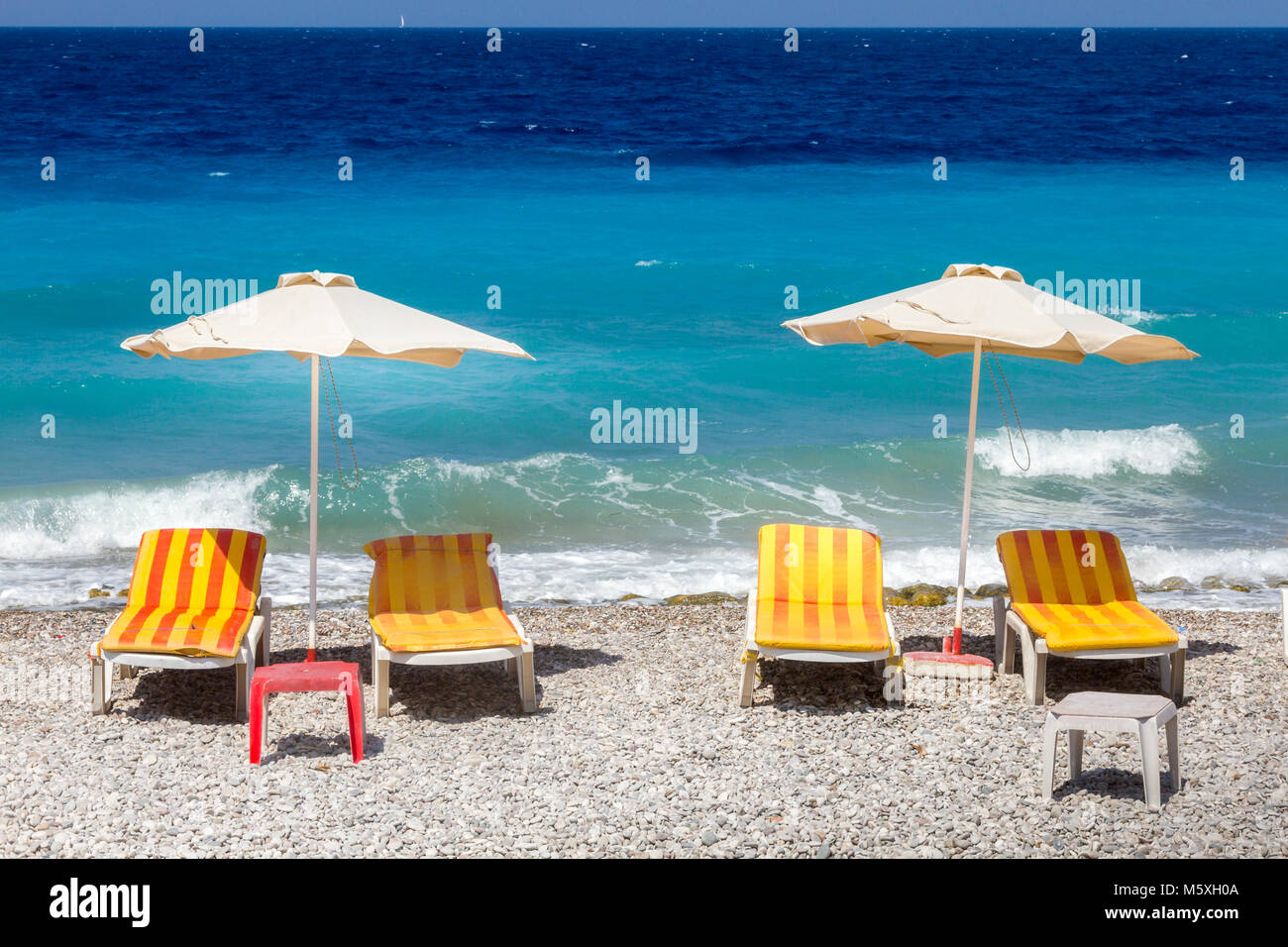 Rhodes, Grèce, chaises longues et parasols à la plage de la ville de Rhodes. Banque D'Images