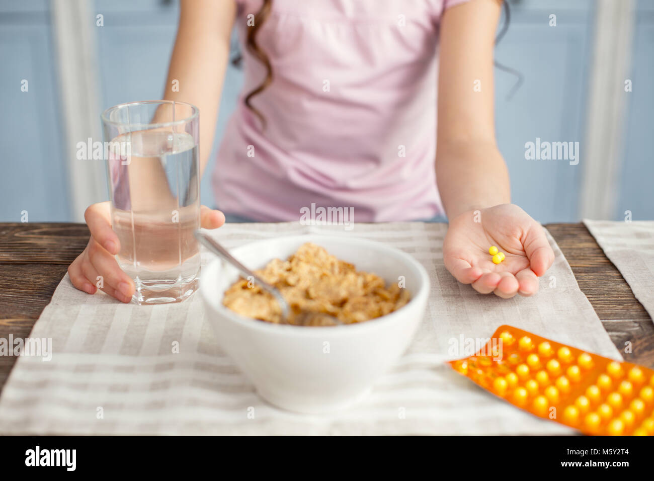 Petite fille tenant un verre d'eau et de vitamines Banque D'Images