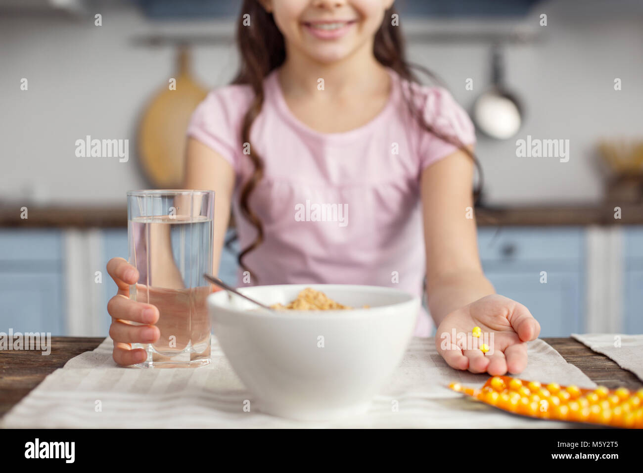 Smiling girl holding un verre d'eau et de vitamines Banque D'Images