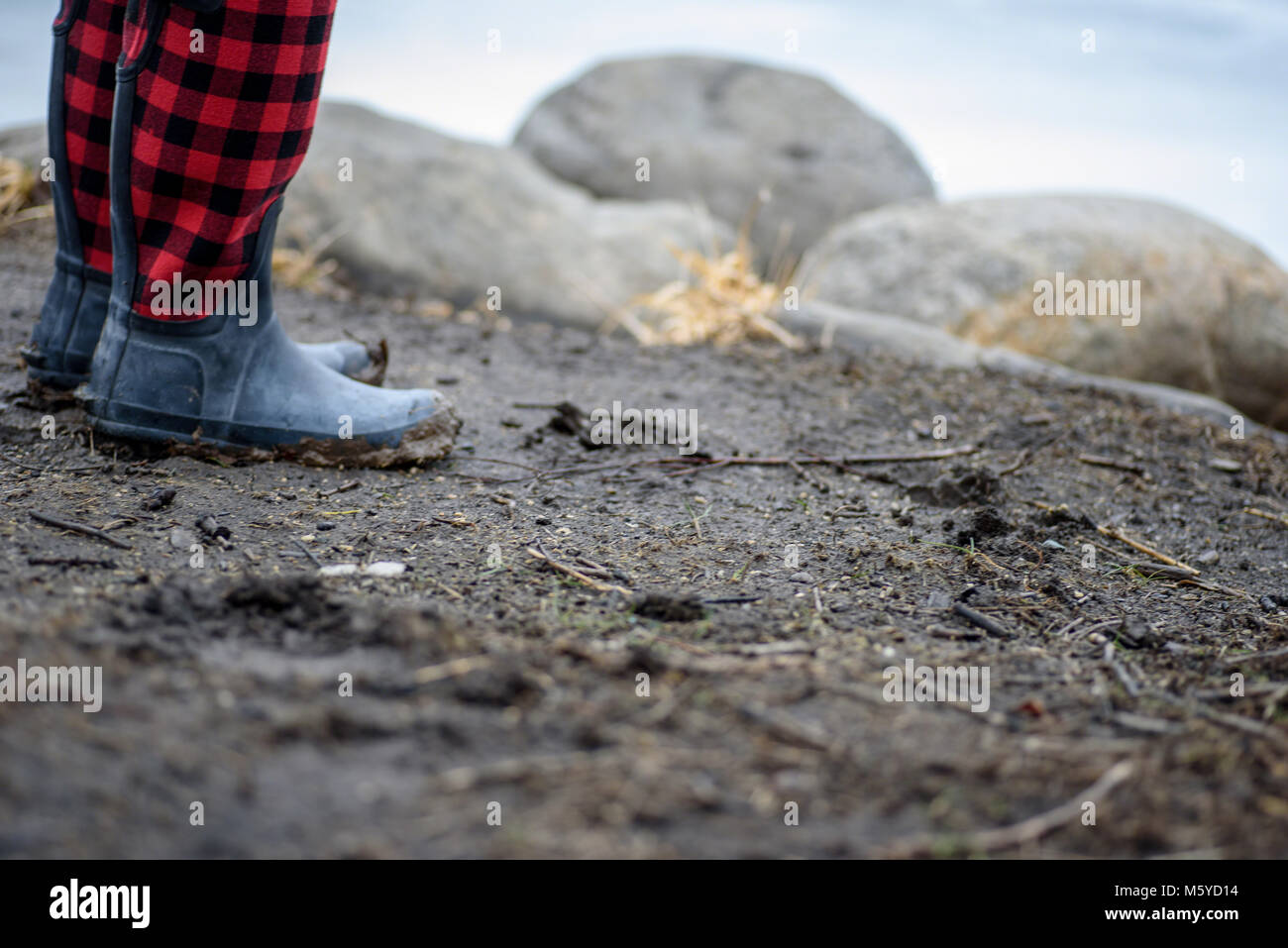 Niveau du sol macro closeup de bottes en caoutchouc wellie plaid le long de côte rocheuse Banque D'Images