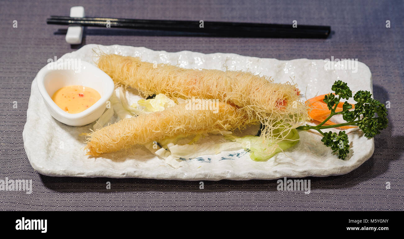 Queues de crevettes frites, salade et crème aigre, servi sur un plat avec les carottes et inaugurés, nappe gris et chopstick background Banque D'Images