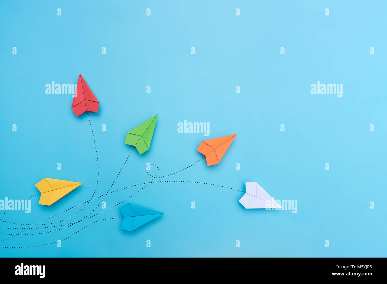 Avions en papier de couleur sur fond bleu. Banque D'Images