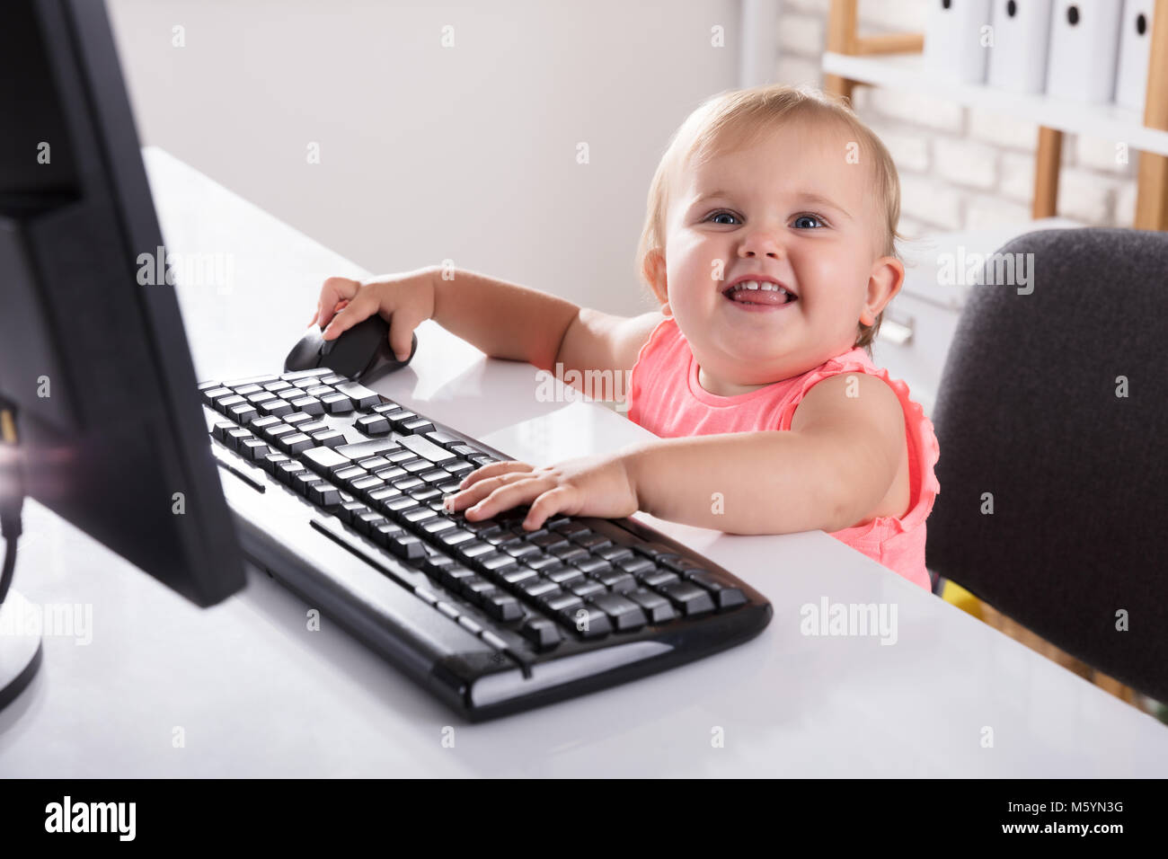 Close-up of Cute Smiling Baby Girl Using Computer Banque D'Images