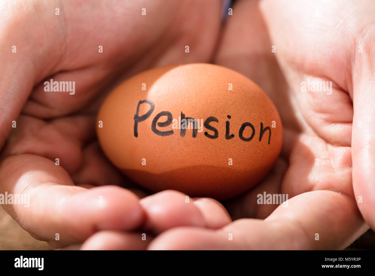 Close-up d'une main humaine avec Brown Egg montrant Texte Pension Banque D'Images