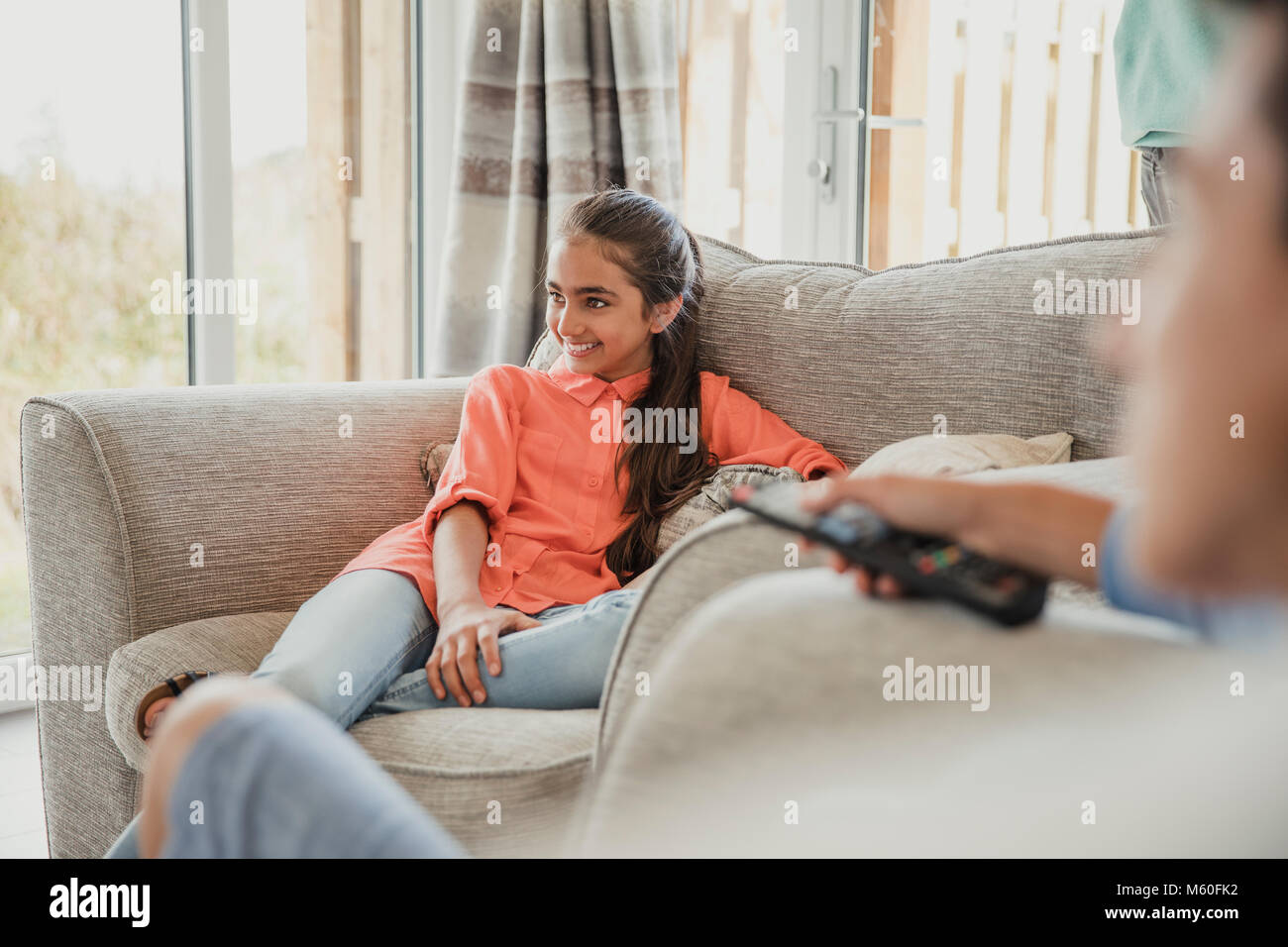 Une adolescente détente en vacances, assis sur le canapé et de rire. Banque D'Images