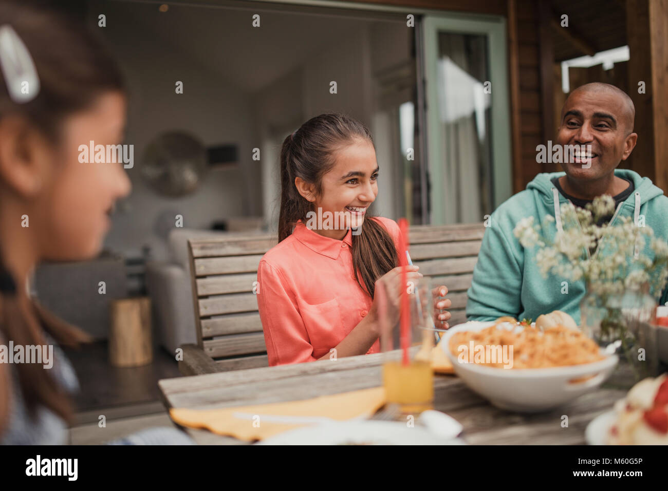 Petite fille rire avec sa famille à la table à l'extérieur holdiay cottage. Banque D'Images