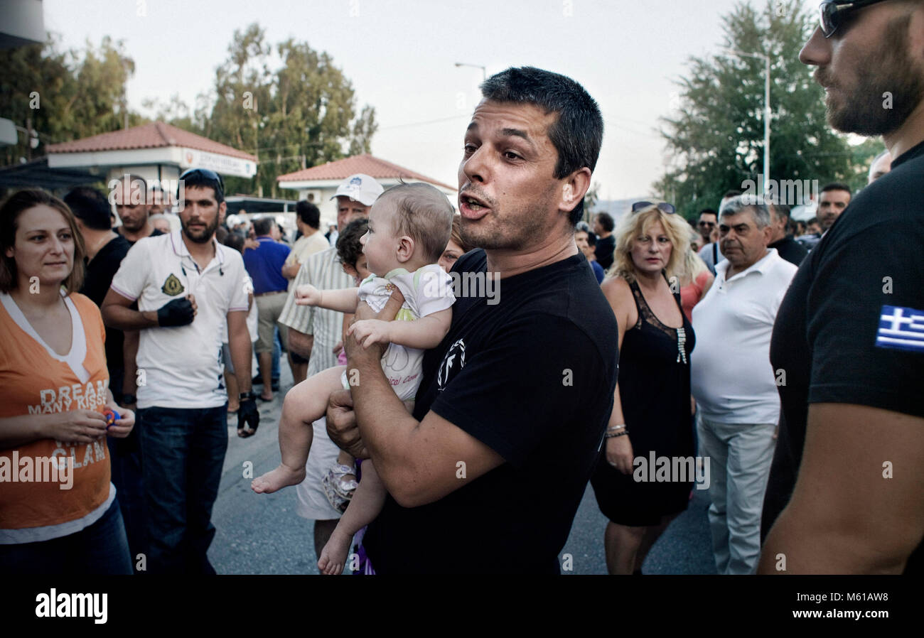 Grèce : Golden Dawn - 24/08/2012 - Grèce / Corinthe - Stathis Boukouras, Corinthe sous-d'Aube dorée est titulaire d'un enfant disant -Tout ce que nous faisons c'est pour eux ! !- au cours d'une manifestation contre la décision du gouvernement de transférer les immigrants dans un camp militaire à l'ouskirts de la ville, le 24 août 2012. Boukouras est un 39 ans, Baker, il est père de trois enfants et il a dit qu'il a seulement fait son entrée au gouvernement pour aider le peuple grec. Il dit qu'il reviendra à son œuvre originale dès qu'il n'est pas nécessaire à la vie politique. - Stefania Mizara / Le Pictorium Banque D'Images