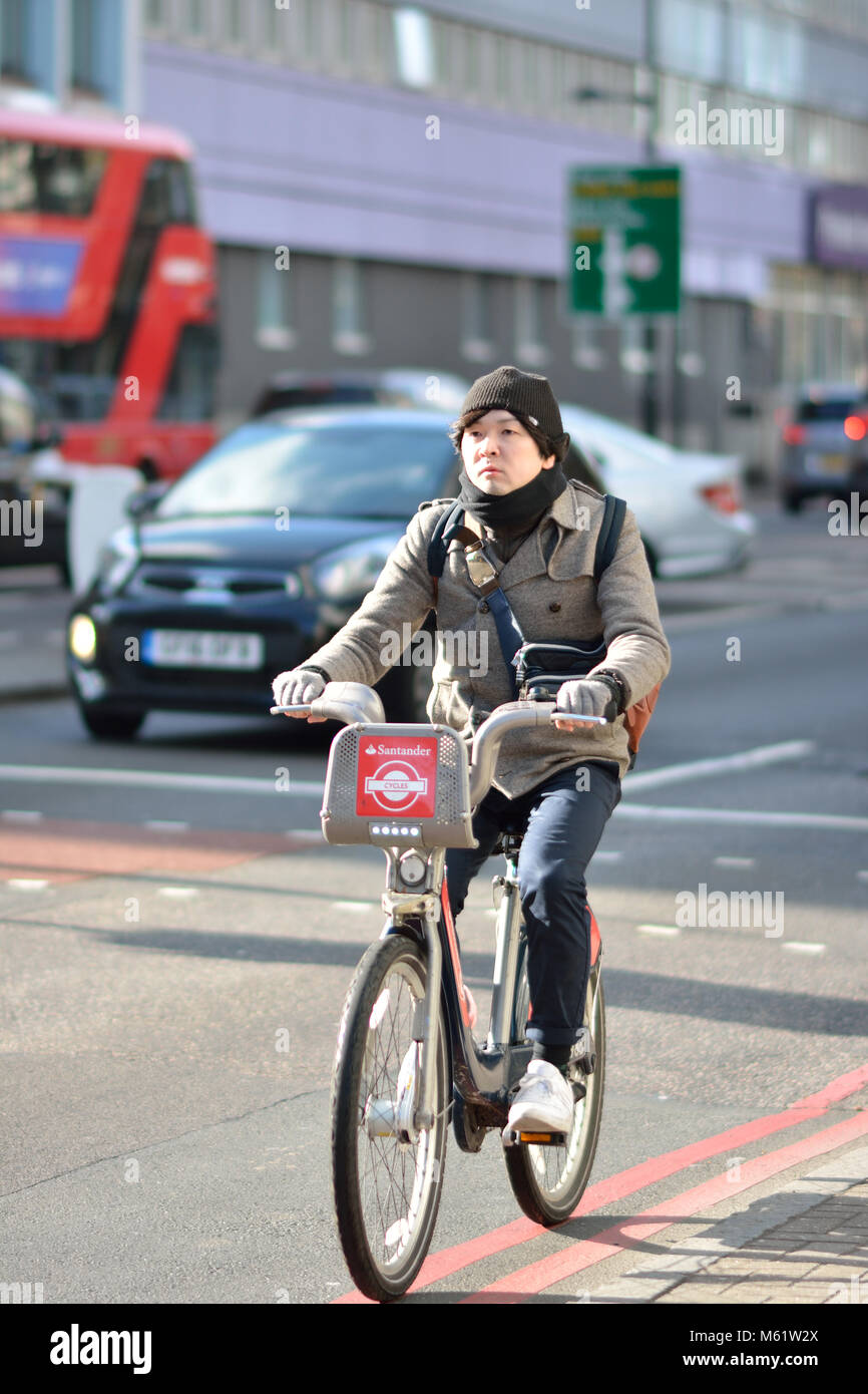 L'homme oriental équitation un vélo de location Santander (boris bike) à Londres, Royaume-Uni Banque D'Images