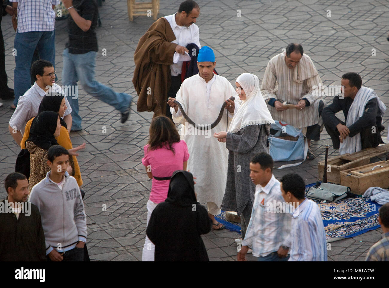 Un charmeur de serpent attire les visiteurs de la place Jemaa el Fna à Marrakech, Maroc pour prendre une photo avec l'un de ses serpents. Banque D'Images