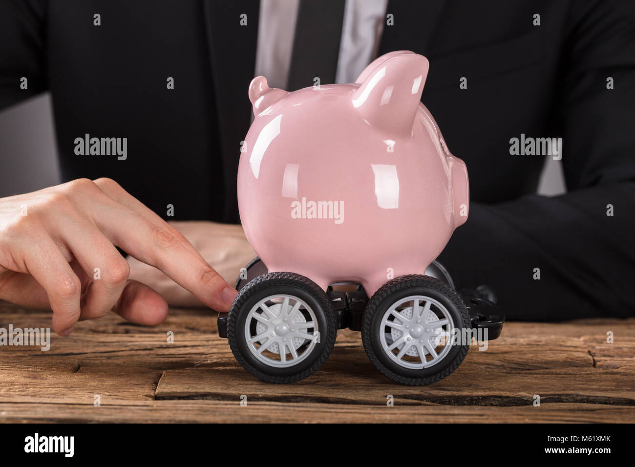 Close-up of Pink Piggy Bank Businessperson poussant sur les roues au 24 Banque D'Images