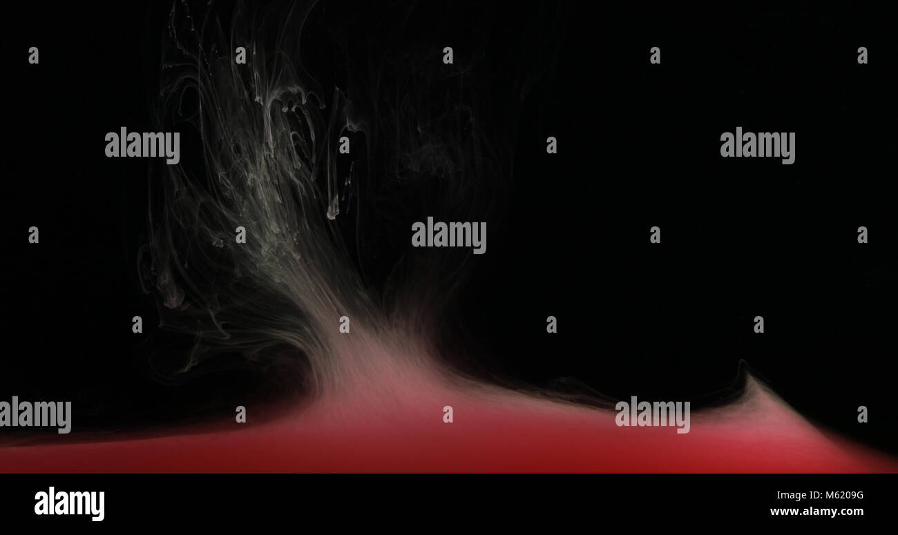 Gouttes rouges, les vagues et les nuages d'encre création de formes dynamiques dans l'eau. Effets abstraits de couleurs de peinture dans un liquide. Studio shot sur fond noir. Banque D'Images