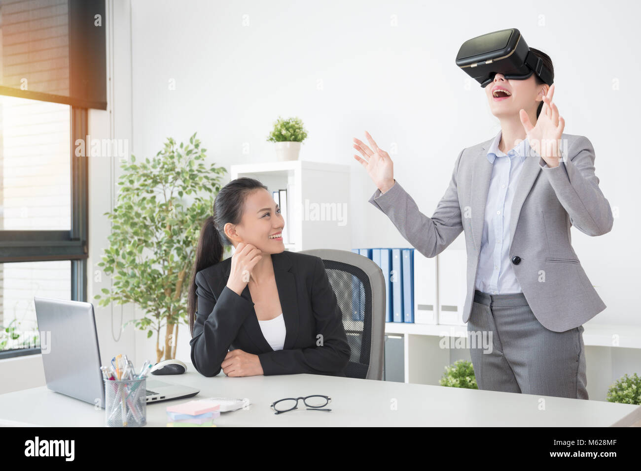 Office de Tourisme d'affaires asiatiques femmes heureux profiter d'essayer de nouvelles lunettes lunettes de VR et de s'amuser avec l'expérience 3D simulation. Banque D'Images