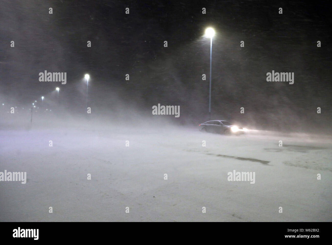 Une voiture passe à travers une tempête de neige à Whitley Bay, comme beaucoup de neige a causé plus de misère pour les voyageurs de la nuit. Banque D'Images
