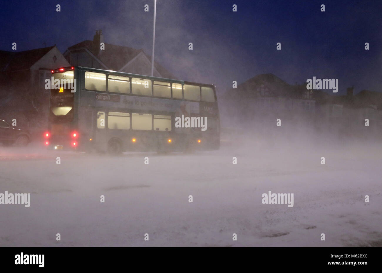 Un bus passe par une tempête de neige à Whitley Bay, comme beaucoup de neige a causé plus de misère pour les voyageurs de la nuit. Banque D'Images