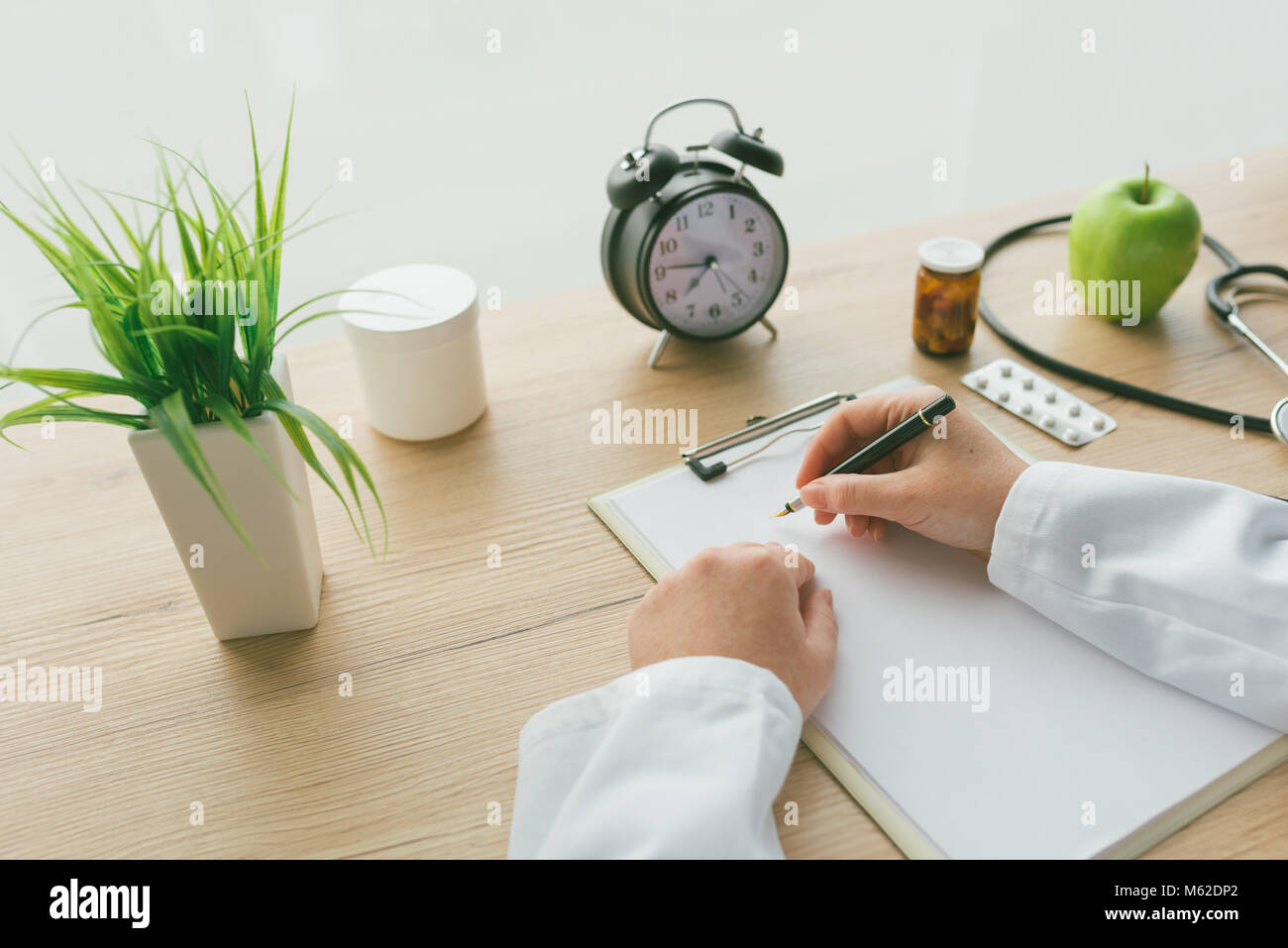 Femme médecin à écrire des notes, les antécédents médicaux du patient ou la médecine prescription sur presse-papiers papier pendant l'examen médical à l'hôpital office Banque D'Images