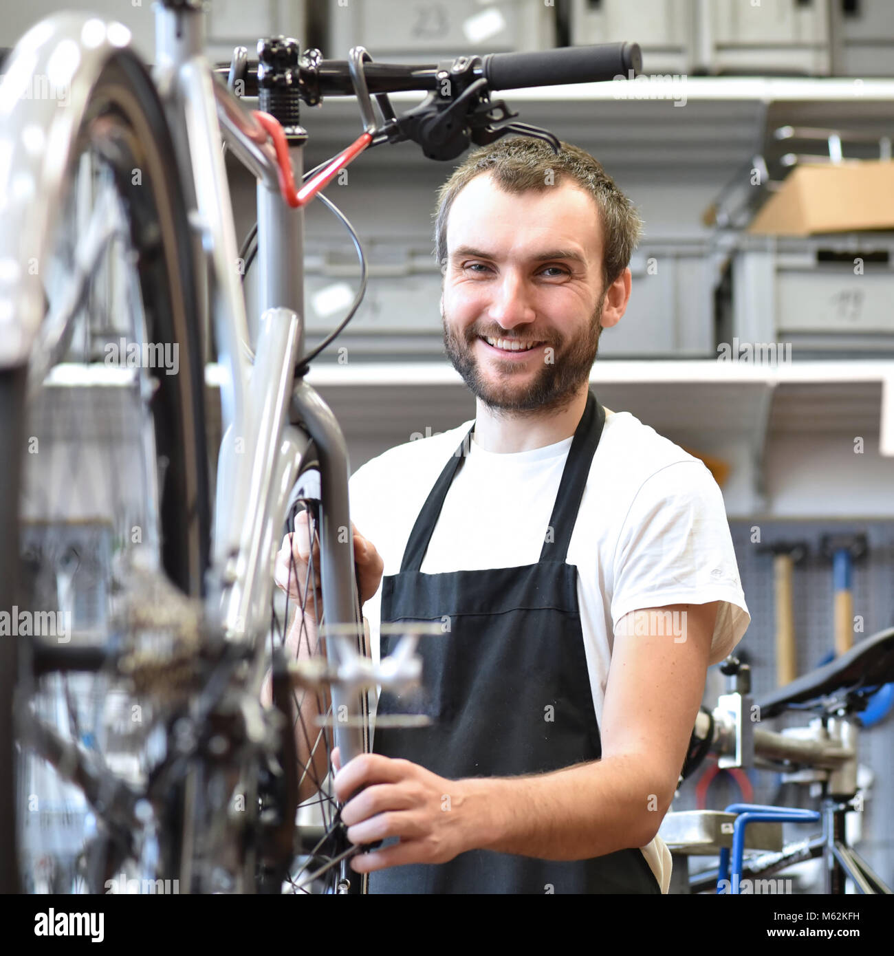 Portrait d'un mécanicien vélo sympa et compétent dans un atelier de réparation de vélo Banque D'Images