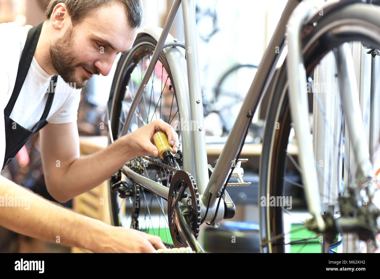 Mécanicien dans un atelier de réparation de bicyclettes de huiler la chaîne d'un vélo Banque D'Images