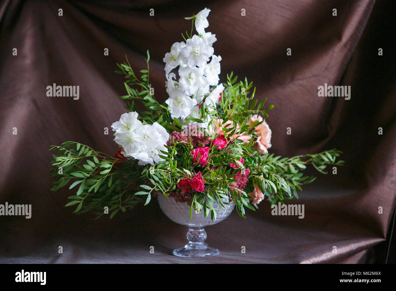 Bouquet de roses asymétriques, œillets, delphinium et hortensias sur un fond brun Banque D'Images