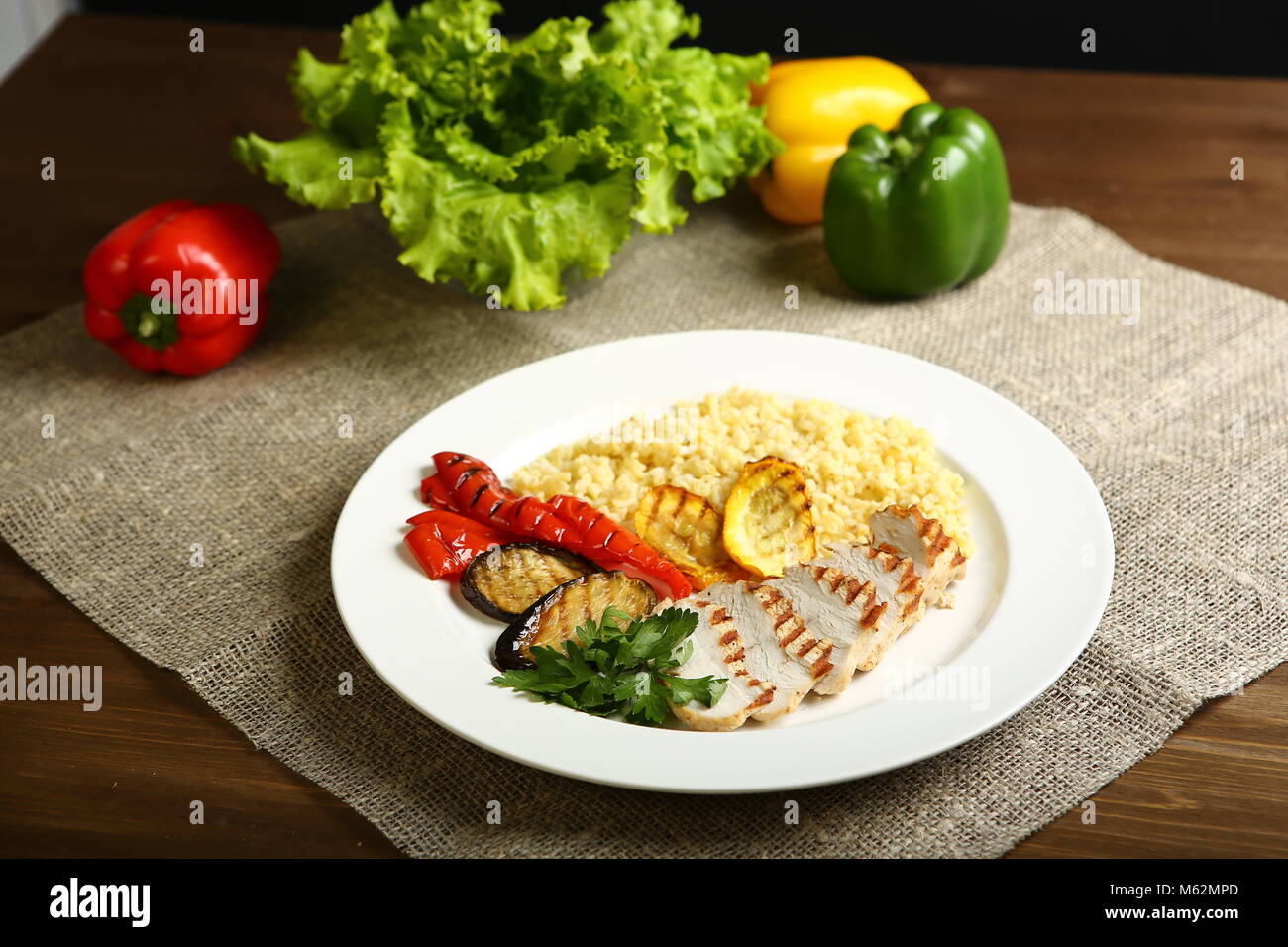 Avec des tranches de poulet grillé, avec légumes, couscous, sur une assiette blanche, décorée de persil. Dans l'arrière-plan, feuilles de laitue, la couleur du poivre. Low-ca Banque D'Images