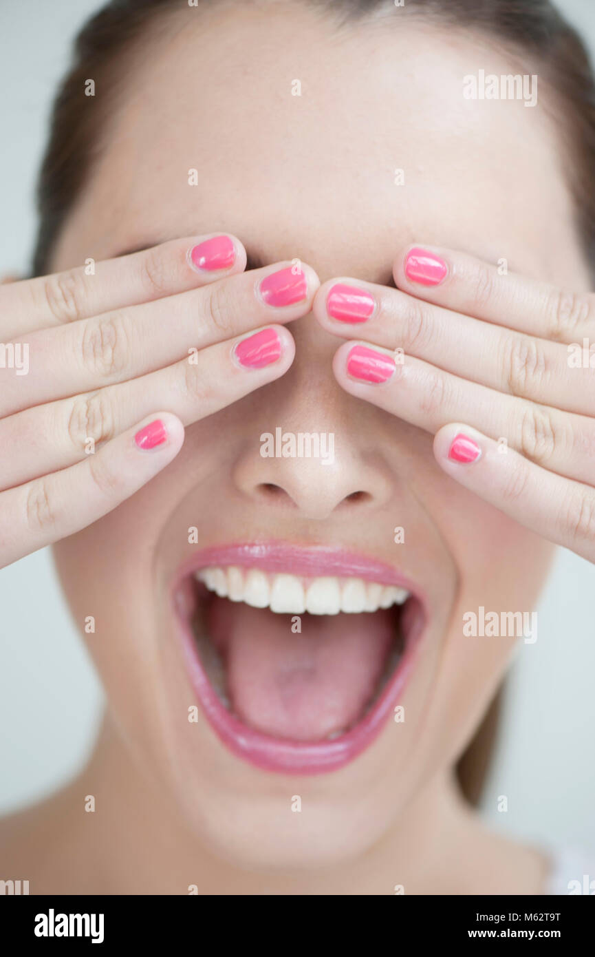 Laughing woman couvrant les yeux avec les mains Banque D'Images