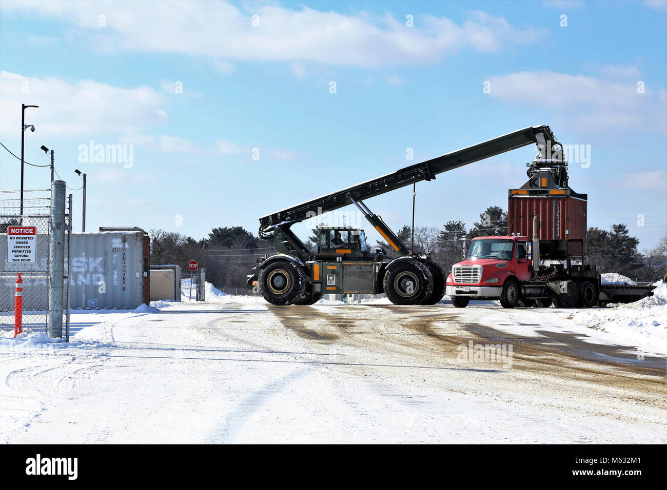 Un opérateur d'équipement lourd avec le Centre de préparation logistique des transports utilise un gestionnaire de chariots élévateurs tous terrains pour conteneurs/Loader pour charger un conteneur sur une remorque près du bâtiment 2100 Le 7 février 2018, à Fort McCoy. Le container/chargeur est capable de soulever certains des plus grands contenants d'expédition et de chargement des conteneurs sur wagons ou remorques soit. (U.S. Army Banque D'Images