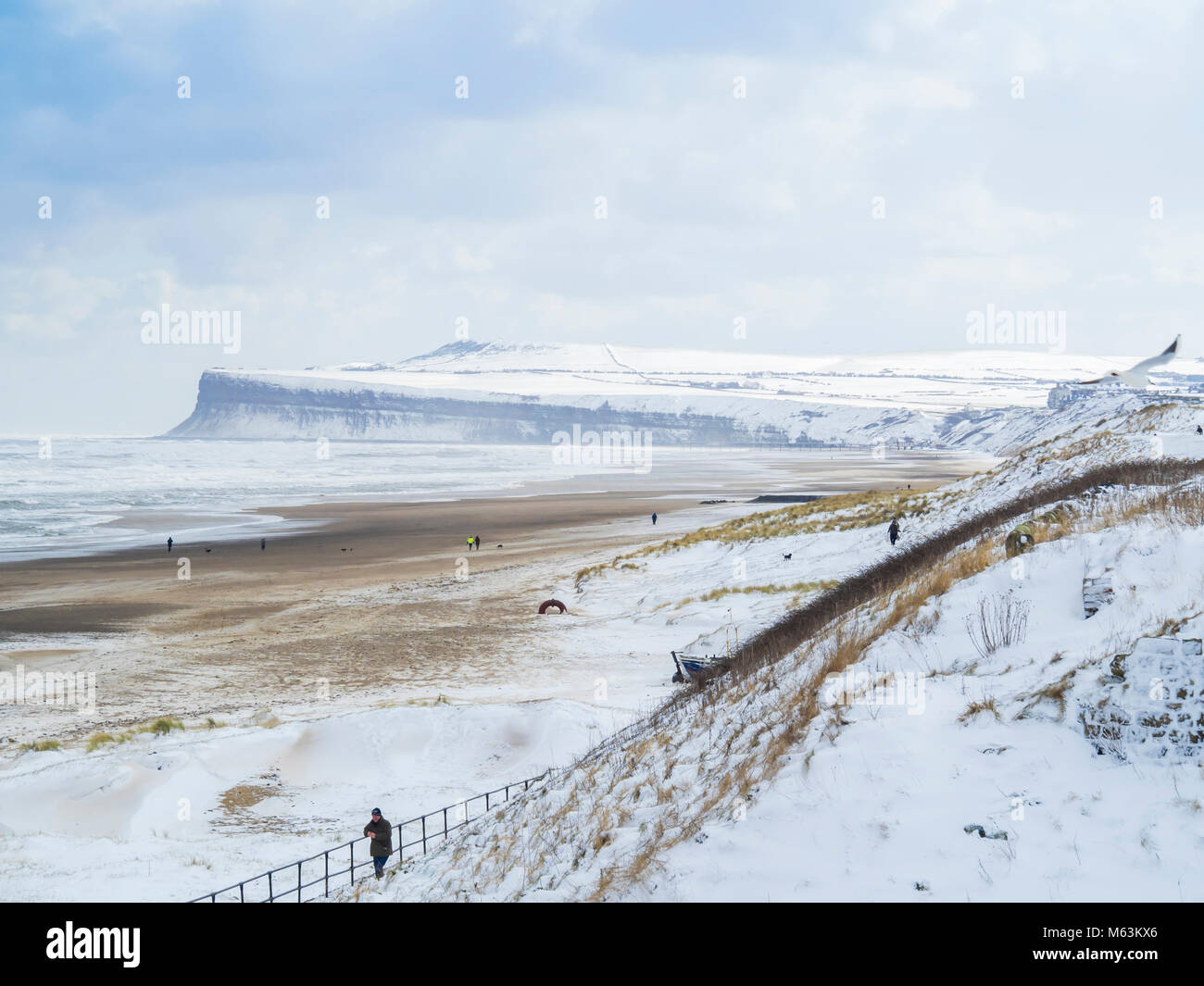Marske by the Sea North Yorkshire UK 28 février 2018 Météo France. Conditions de neige continue avec un fort vent d'est pour faire froid sur une plage déserte avec snowy falaise et une vue sur parc éolien offshore de Redcar, nuages noirs sur l'horizon s'acquitter d'autres chutes de neige à venir. Crédit : Peter Jordan NE/Alamy Live News Banque D'Images