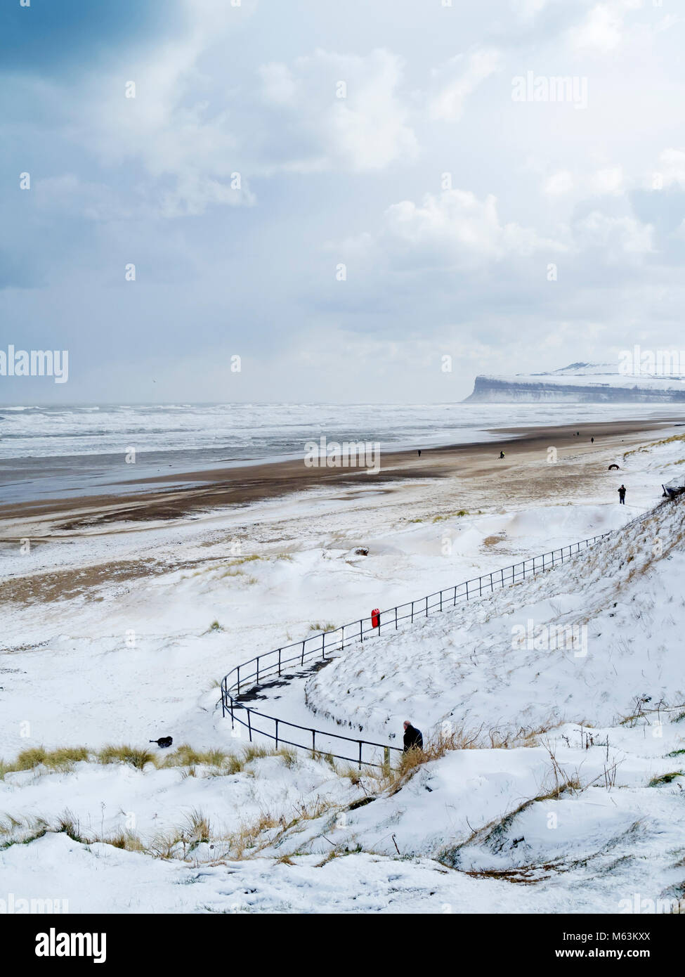 Marske by the Sea North Yorkshire UK 28 février 2018 Météo France. Conditions de neige continue avec un fort vent d'est faire pour des conditions froides pour les gens marcher les chiens sur la plage. Nuages noirs sur l'horizon s'acquitter d'autres chutes de neige à venir. Crédit : Peter Jordan NE/Alamy Live News Banque D'Images
