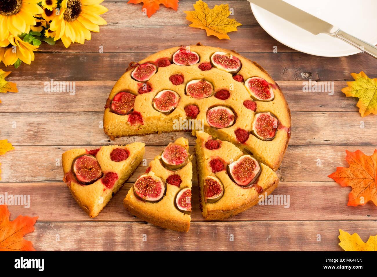 Couper des Fig et framboise cake avec le plateau et couteau à gâteau et un bouquet de tournesols et feuilles d'automne comme décoration d'automne. Banque D'Images