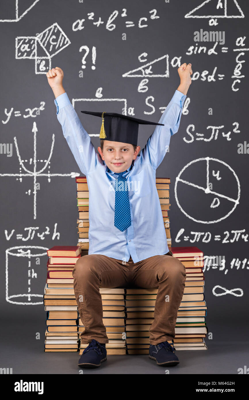 Mathématiques Éducation concept. Des formules mathématiques, des dessins et graphiques derrière un garçon assis sur un trône de books Banque D'Images