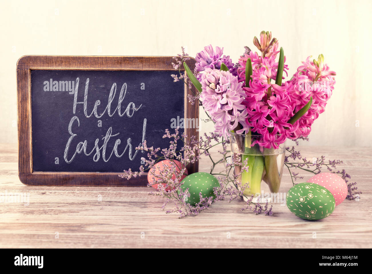 Tableau et bouquet de fleurs de jacinthe sur fond neutre, texte 'Joyeuses Pâques' sur le tableau noir. Banque D'Images