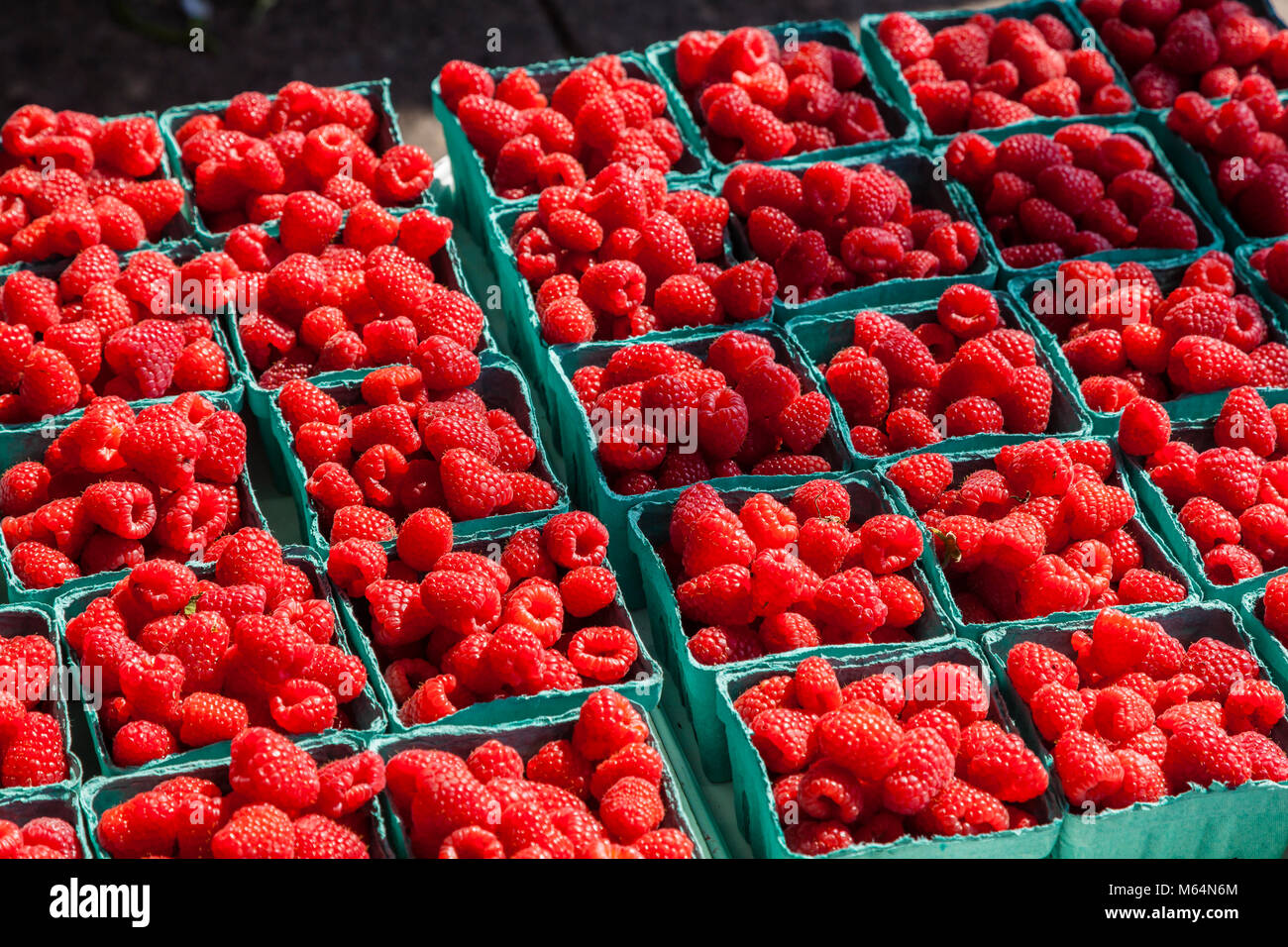 Les framboises rouges en quart des conteneurs dans un marché de producteurs en plein air. Banque D'Images