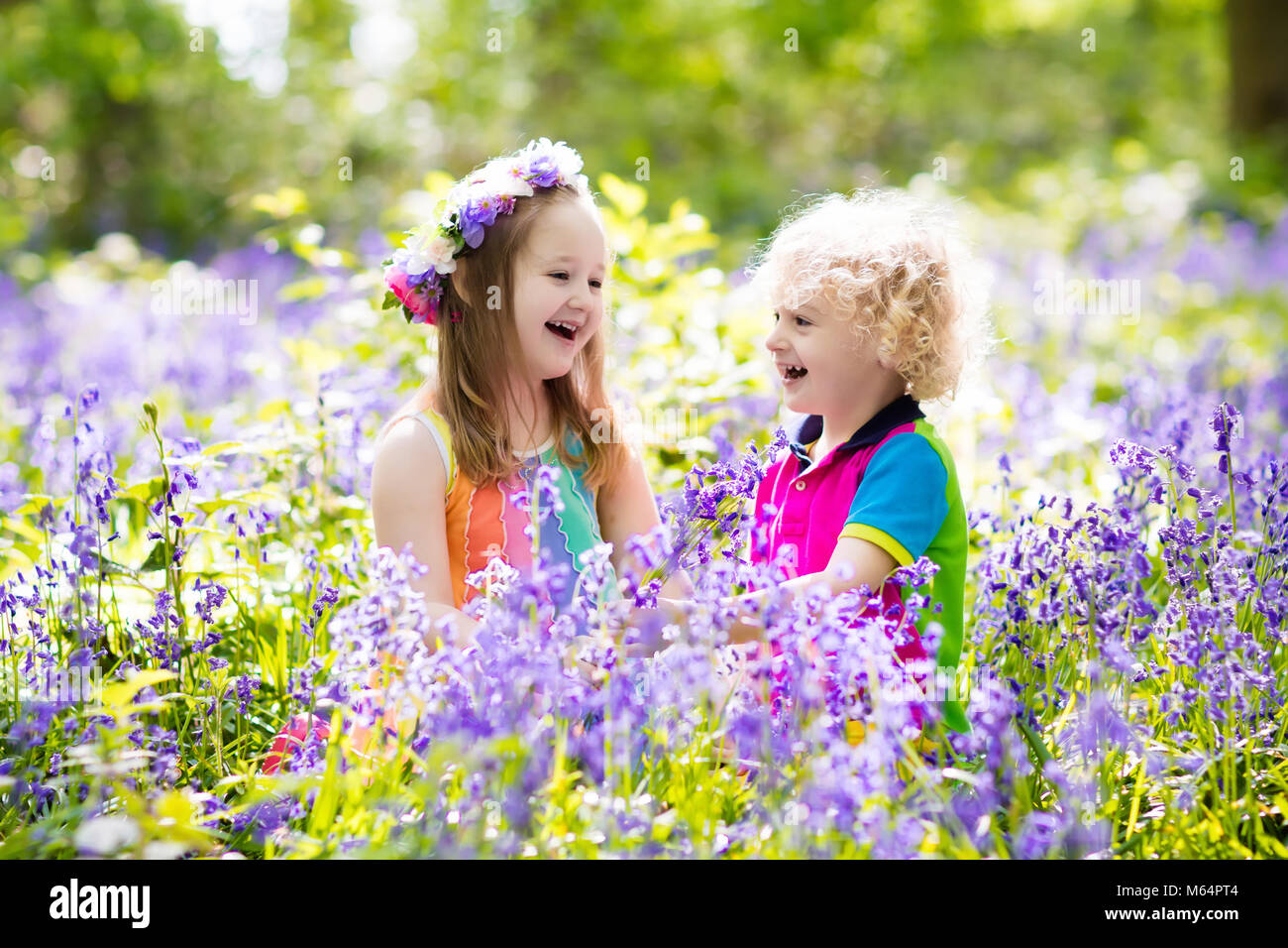 Les enfants avec bluebell flowers, outils de jardin et de brouette. Garçon et fille du jardinage. Les enfants jouent en plein air, travail, jacinthes d'eau et de l'usine blue bell Banque D'Images