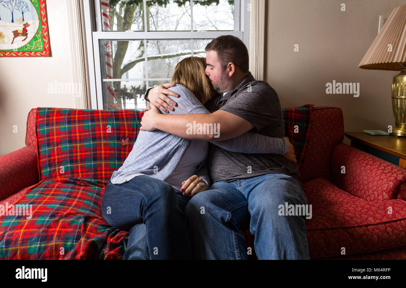 Un jeune couple attend avec enthousiasme et prie pour une bonne nouvelle, car ils sont assis sur leur canapé du salon. Banque D'Images