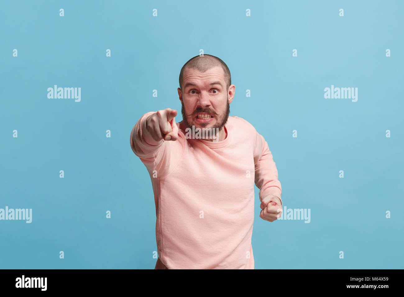L'homme dominateur et vous voulez vous point, demi-longueur closeup portrait sur fond bleu. Banque D'Images