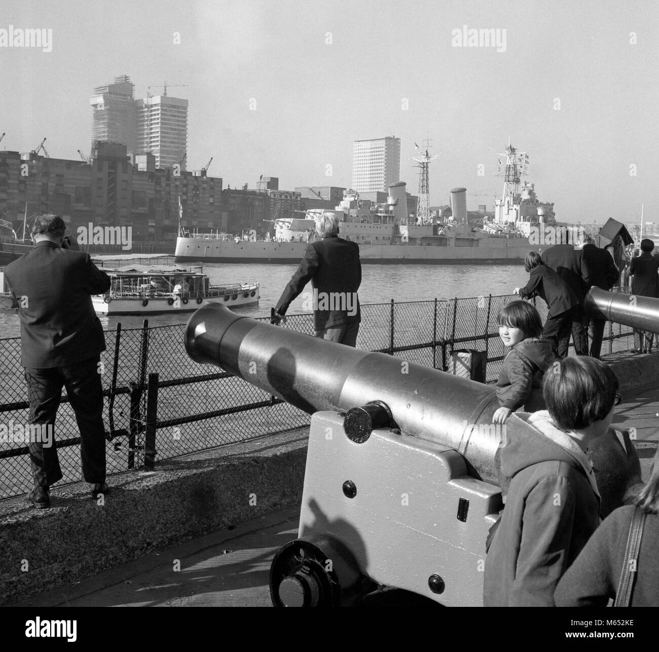 Les Londoniens s'en tenir à l'vieux fusils de la Tour de Londres pour donner la bienvenue à HMS Belfast, après qu'elle avait passé par le Tower Bridge à son amarrage finale pour devenir un musée flottant. Banque D'Images