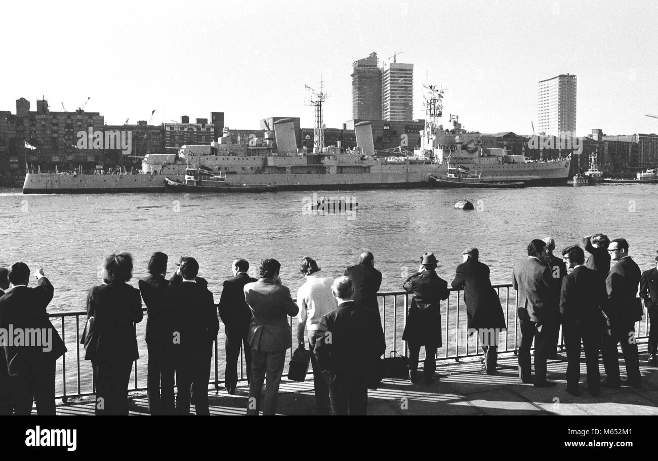 Les Londoniens près de la Tour de Londres donnent un Bienvenue sur le HMS Belfast, la dernière de la Royal Navy's big-gun croiseurs, comme elle arrive à sa dernière amarre près de Tower Bridge, où elle deviendra un musée flottant. Banque D'Images