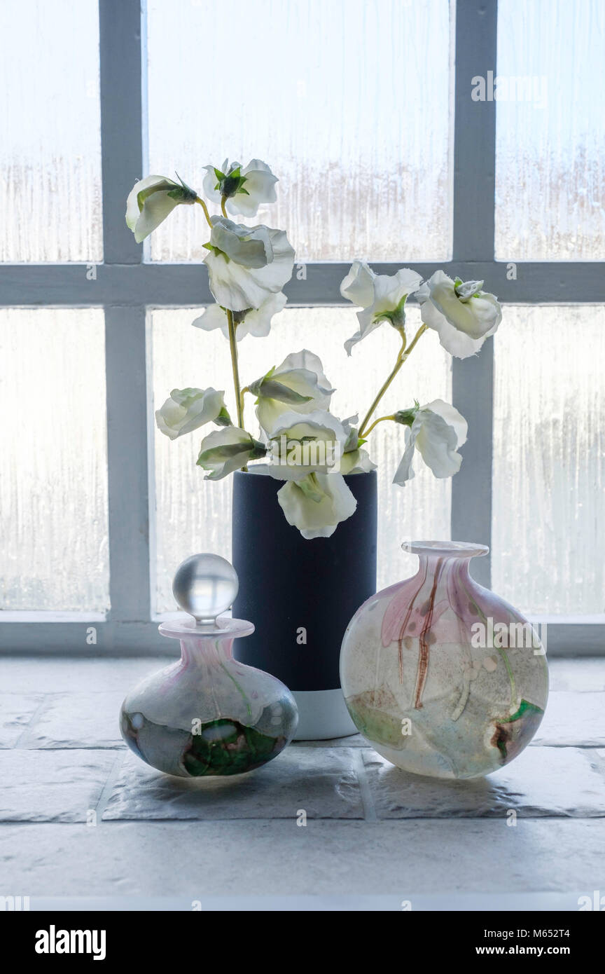 STILL LIFE sur rebord de fenêtre, SALLE DE BAINS AVEC ÎLE DE WIGHT Flacons à parfum EN VERRE BLANC ET FLEURS ARTIFICIELLES DANS UN VASE Banque D'Images