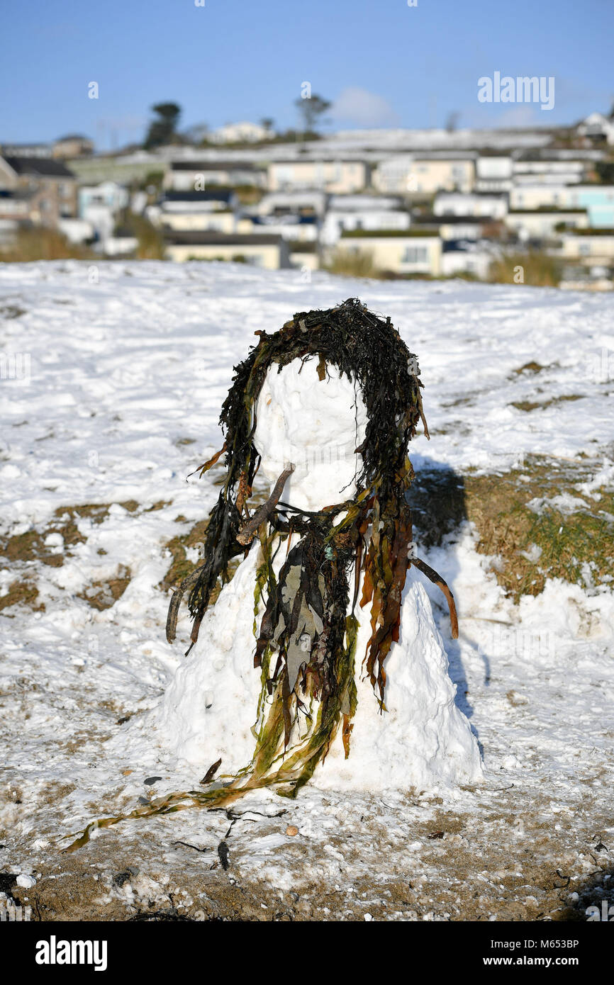 Un bonhomme de neige avec des cheveux d'algues et un foulard sur une plage de Marizion enneigée, dans les Cornouailles, comme le plus haut niveau d'avertissement météorologique a été émis pour l'Écosse et l'Irlande, alors que les prévisionnistes avertissent de conditions de « blizzard ». Banque D'Images