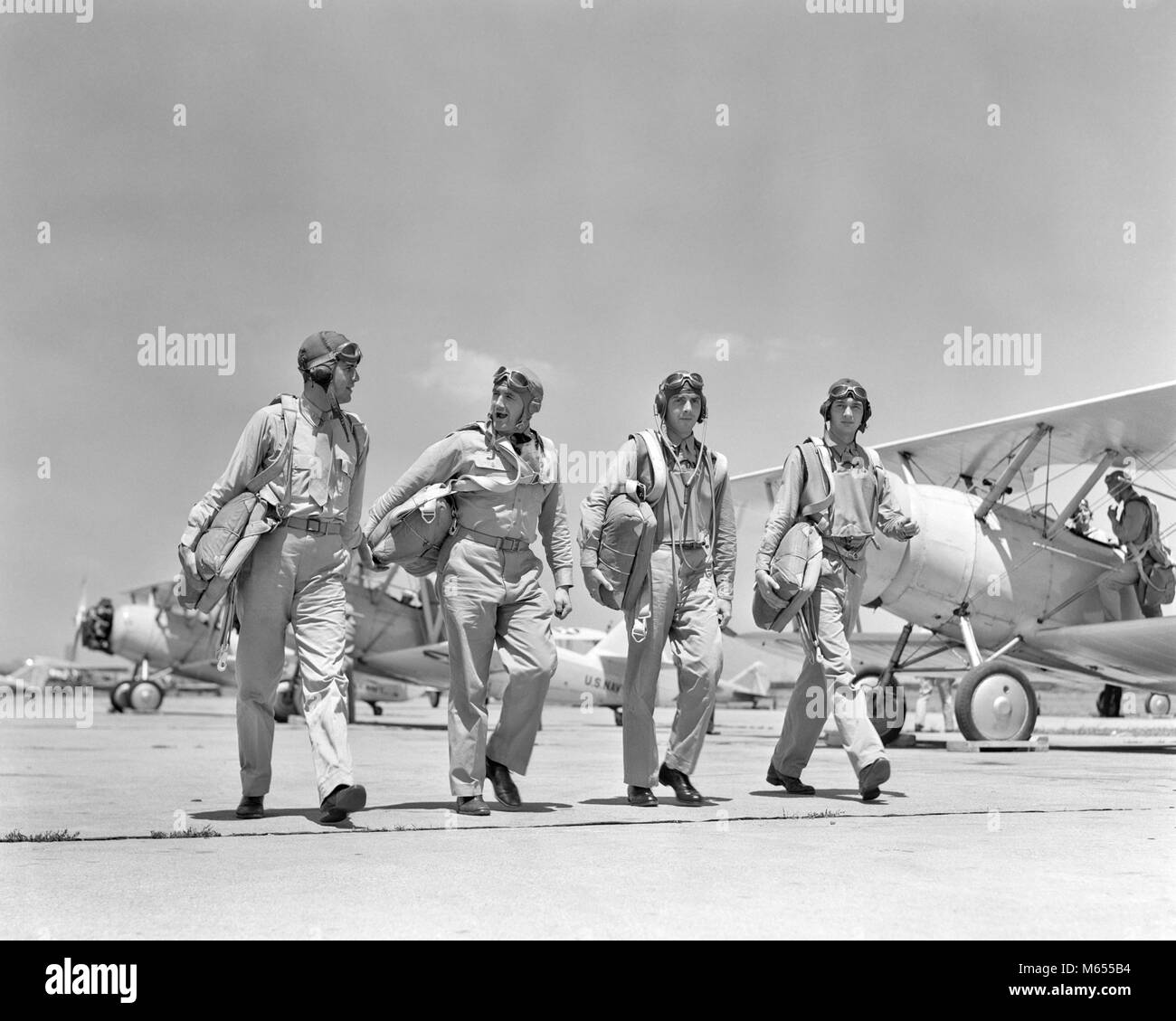1940 QUATRE PILOTES DE LA MARINE AMÉRICAINE À MARCHER ENSEMBLE SUR LE TARMAC DE RETOUR DE MANOEUVRES D'AIR AU PHILADELPHIA NAVY YARD PA USA - UN1711 HAR001 HARS 30-35 ANS AVENTURE PILOTES HISTORIQUE AVIATION TARMAC PA LA COOPÉRATION DES UNIFORMES DES AGENTS DE PETIT GROUPE DE PERSONNES ADULTES MI-hommes mi-homme revenant ADULTES YOUNG ADULT MAN AVIONS BIPLANS N&B NOIR ET BLANC PORTRAIT DE L'ORIGINE ETHNIQUE DES PERSONNES À L'ANCIENNE DES MANOEUVRES Banque D'Images