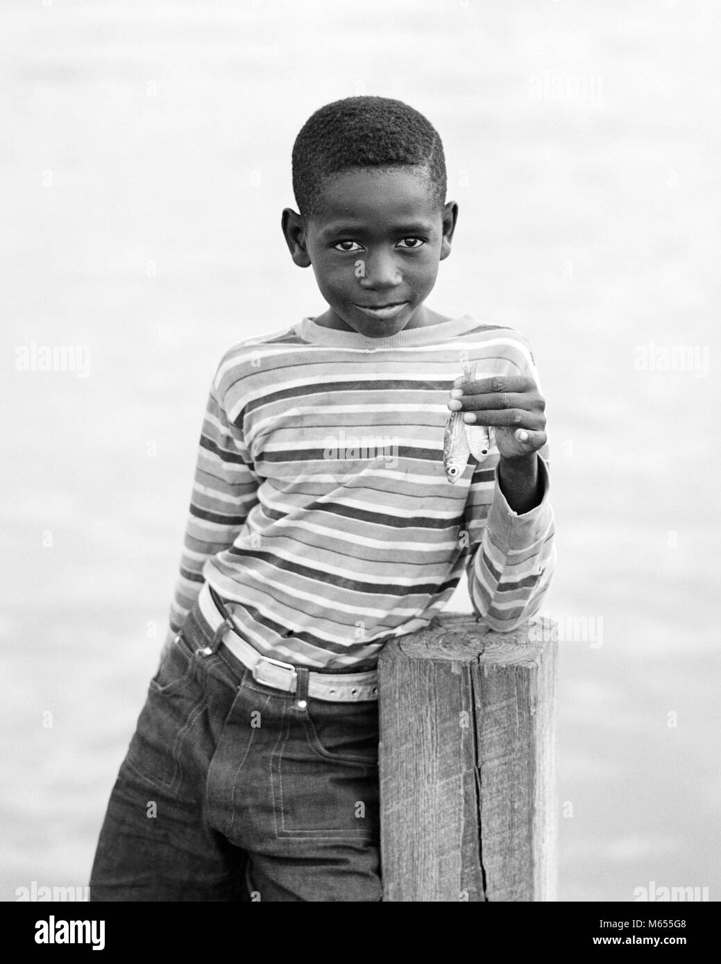 1970 garçon des Bahamas en chemise rayée à l'expression du visage triste à la caméra SUR UN QUAI À LA TENUE DE DEUX très petits poissons - un HAR8177001 HARS NOSTALGIE TRÈS CONTACT OCULAIRE 10-12 ans 7-9 ans PRETEEN BOY SIZE BONHEUR DEUX ANIMAUX BAHAMAS africains-américains africains-américains DES LOISIRS NOIR ORIGINE AMÉRICAINS AFRICAINS AFRICAN AMERICAN PRIDE JOYEUX SOURIRES juvéniles mâles minuscules pré-ADO PRE-TEEN BOY B&W NOIR ET BLANC DES BAHAMAS À LA CAMÉRA À Old Fashioned Banque D'Images