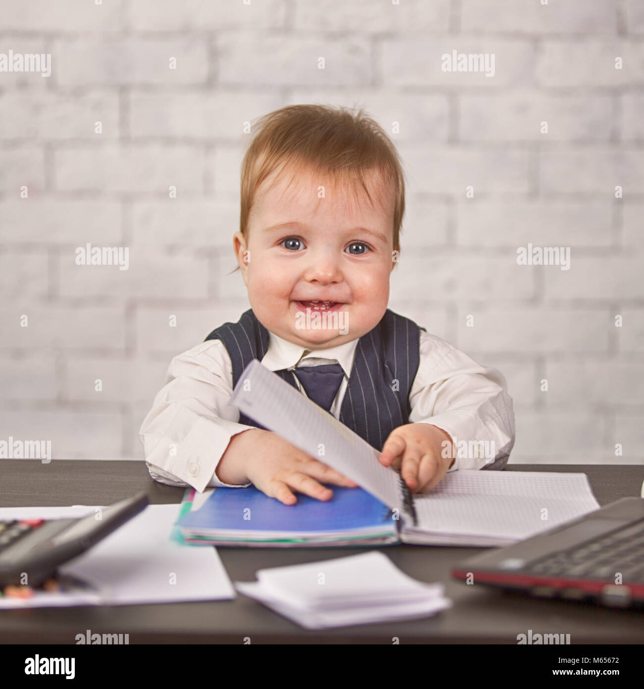 Cute blonde un enfant dans un costume d'affaires est assis au bureau